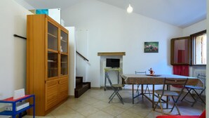 Un salon avec un meuble en bois, une table à manger avec des chaises, une cheminée et un escalier.