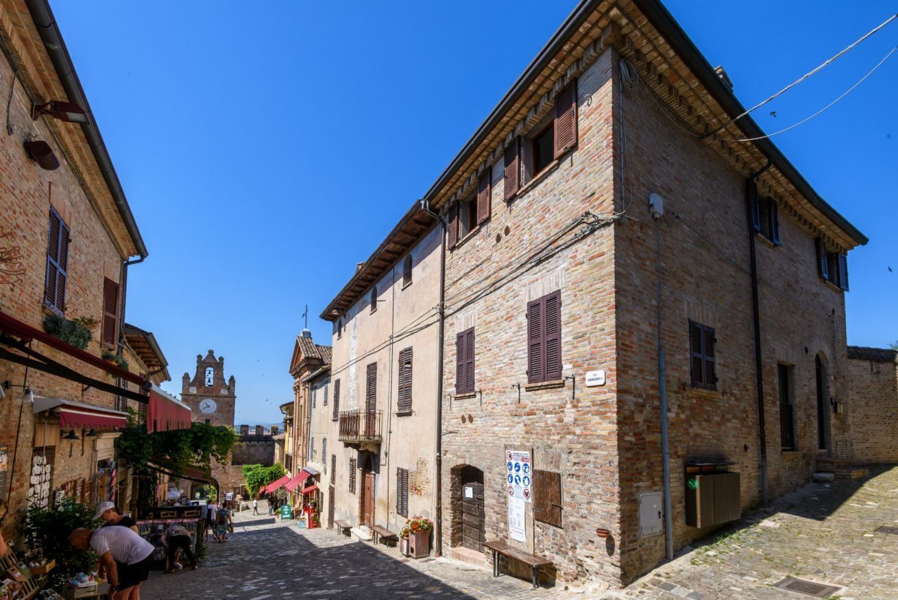 A cobblestone street with historic buildings, a clock tower, and outdoor seating.