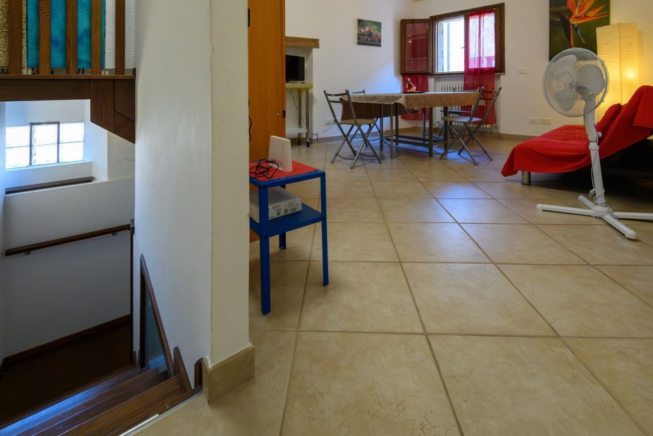 A living room with a dining area, a staircase, and a fan.