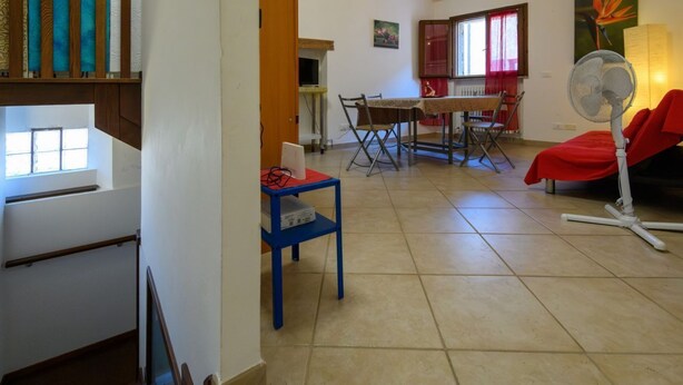 Un salon comprenant un coin repas, un escalier et un ventilateur.