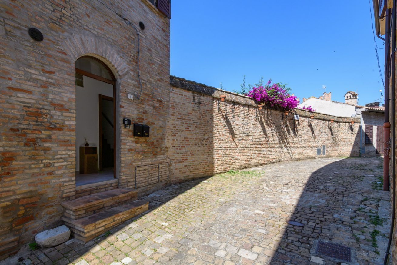 Une ruelle étroite pavée de pierres, avec un bâtiment en briques d’un côté.