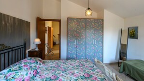 Une chambre à coucher comprenant un lit, une armoire, un luminaire suspendu et une chaise.