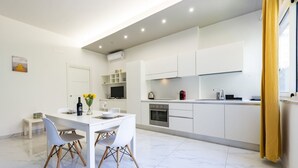 A modern kitchen with white cabinetry, a dining table with chairs, and a small seating area. - GuestHost - Charming 64 sqm apartment, ideal for three people, located on the mezzanine floor of a building without a lift.The property is located in a privileged position, close to Piazza della Rinascita, the hub of city life in Pescara, and a stone's t (Pescara)