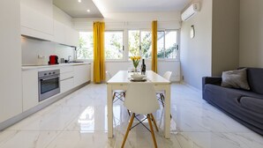 A modern kitchen with white cabinets, a dining table with chairs, and a grey sofa. - GuestHost - Charming 64 sqm apartment, ideal for three people, located on the mezzanine floor of a building without a lift.The property is located in a privileged position, close to Piazza della Rinascita, the hub of city life in Pescara, and a stone's t (Pescara)