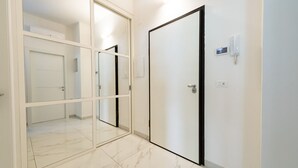 A hallway with a mirrored closet door, a white door, and a wall-mounted phone. - GuestHost - Charming 64 sqm apartment, ideal for three people, located on the mezzanine floor of a building without a lift.The property is located in a privileged position, close to Piazza della Rinascita, the hub of city life in Pescara, and a stone's t (Pescara)