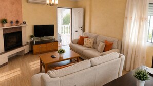 Una sala de estar con sofá, mesa de centro, televisión, chimenea y lámpara de techo.