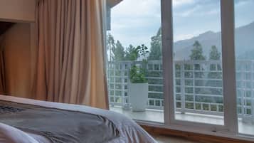 Une chambre avec un grand lit, un plafond en bois et un balcon offrant une vue sur les montagnes.