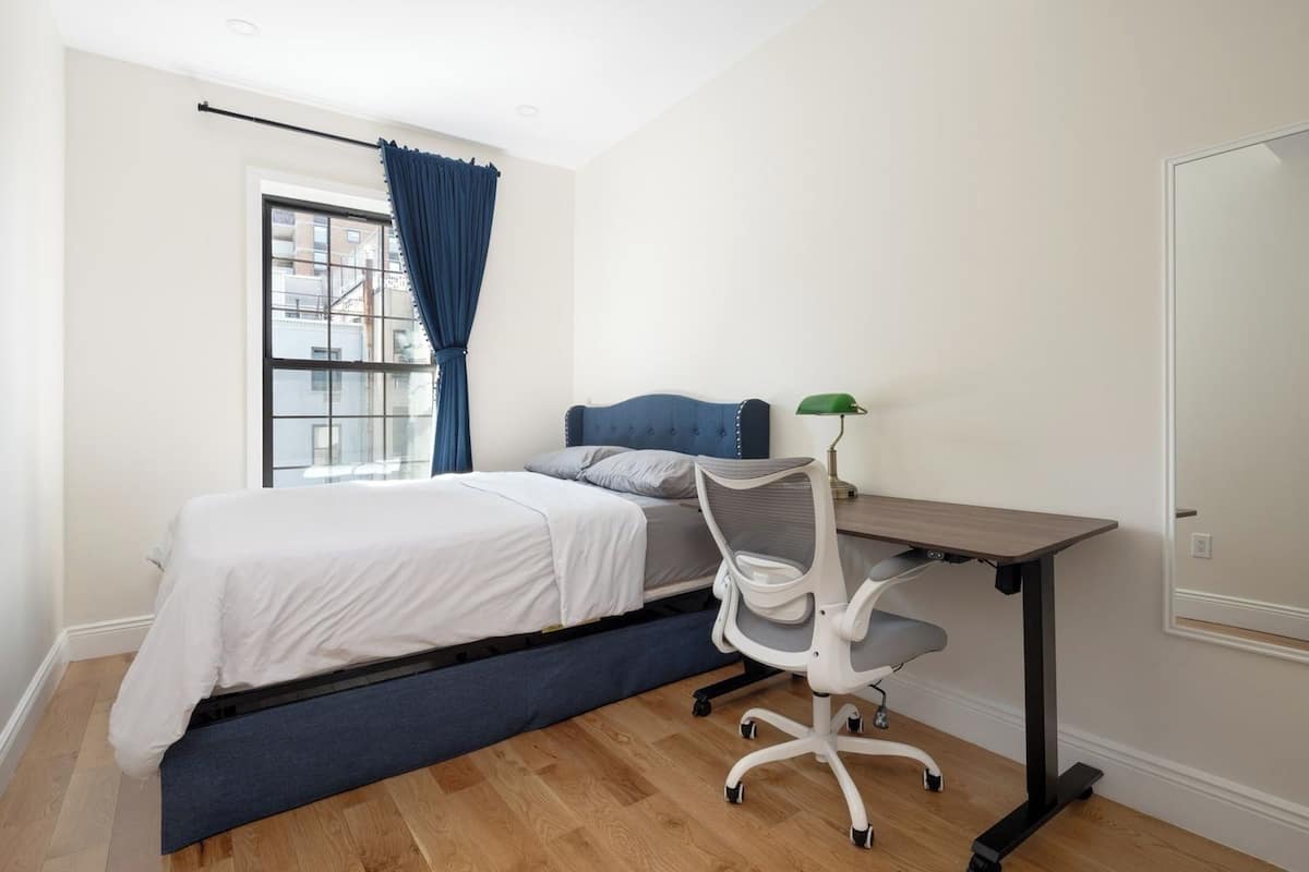 A bedroom with a bed, a desk, and a chair.