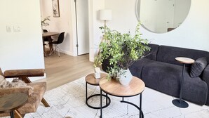 Un salon moderne avec un canapé gris foncé, un miroir rond et une petite table basse en bois.