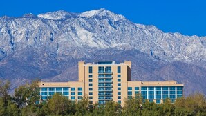 A modern building with a central atrium and multiple floors, surrounded by trees and mountains in the background. - Golf Course Views, Pool, Spa, Dine Al Fresco (Rancho Mirage)