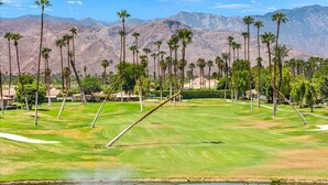 A golf course with a pond, palm trees, and mountains in the background. - Golf Course Views, Pool, Spa, Dine Al Fresco (Rancho Mirage)