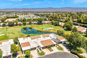 A residential area with houses, a golf course, and a large body of water.