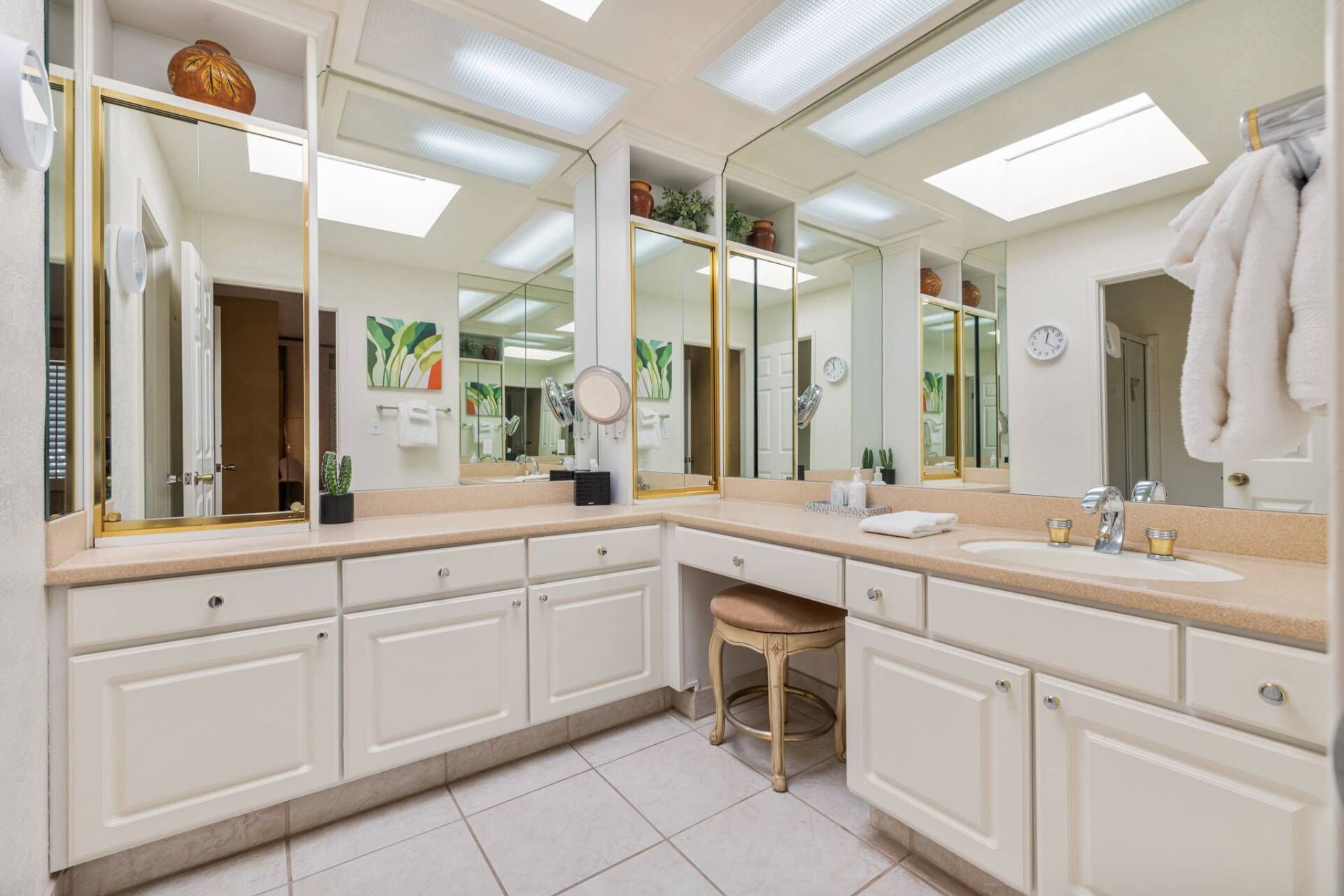 A spacious bathroom with a large vanity, multiple mirrors, and a sink.