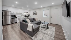 A modern kitchen with white cabinets, a stainless steel refrigerator, and a microwave.