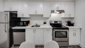 A modern kitchen with white cabinets, stainless steel appliances, and a built-in oven.