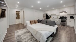 A modern bedroom with a large bed, a sitting area, and a kitchenette.