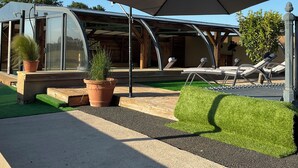 A modern outdoor area with a covered seating area, a glass-enclosed structure, and potted plants. - Let yourself be transported to the heart of Berry and discover our heritage. (Pouligny-Notre-Dame)