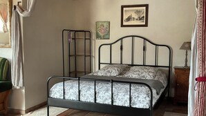 A bedroom with a metal bed frame, a nightstand, a lamp, and a picture on the wall. - Let yourself be transported to the heart of Berry and discover our heritage. (Pouligny-Notre-Dame)