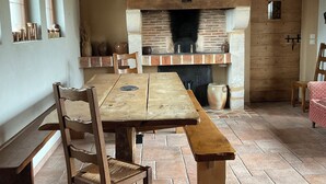 A rustic kitchen with a wooden table, chairs, and a brick fireplace. - Let yourself be transported to the heart of Berry and discover our heritage. (Pouligny-Notre-Dame)