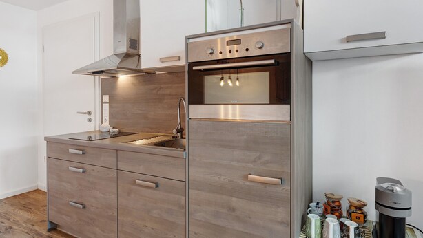 Una cocina con campana extractora de acero inoxidable, horno y lavavajillas integrado.
