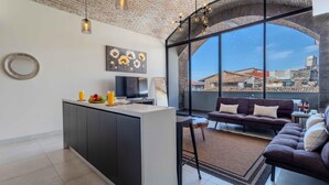 A modern living space with a kitchen island, a dining area, and a seating area with a view of the city. - Bliss 450 - Unit 2-3 Casa NuevaYol 1BD Condo for rent in Downtown, Puerto vallar (Puerto Vallarta)
