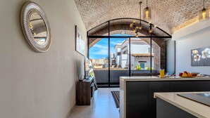 A modern kitchen with a large island, a hanging light fixture, and a view through an arched doorway to the outside. - Bliss 450 - Unit 2-3 Casa NuevaYol 1BD Condo for rent in Downtown, Puerto vallar (Puerto Vallarta)