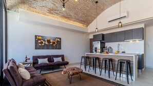 A modern living room with a sectional sofa, a coffee table, and a kitchen area with a bar stool setup. - Bliss 450 - Unit 2-3 Casa NuevaYol 1BD Condo for rent in Downtown, Puerto vallar (Puerto Vallarta)