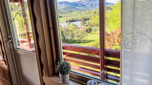 A wooden cabin with a large window overlooking a scenic landscape, a small potted plant, and three metal cups on the windowsill. - Tussebu by Interhome (Tysnes)