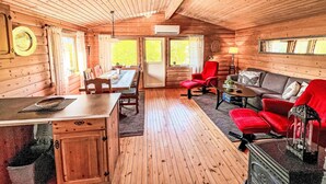 A cozy cabin interior with a dining area, a seating area with a red chair, and a large window. - Tussebu by Interhome (Tysnes)
