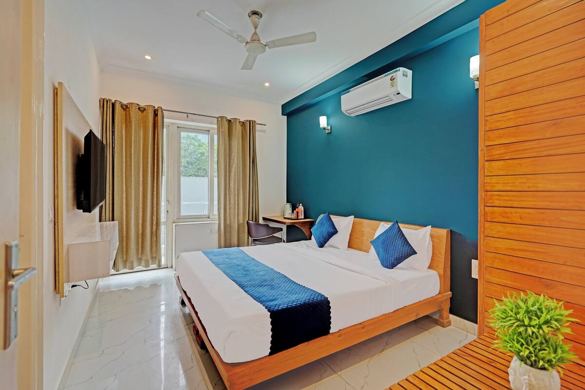 Una habitación de hotel con cama, escritorio, silla, aire acondicionado y ventilador de techo.