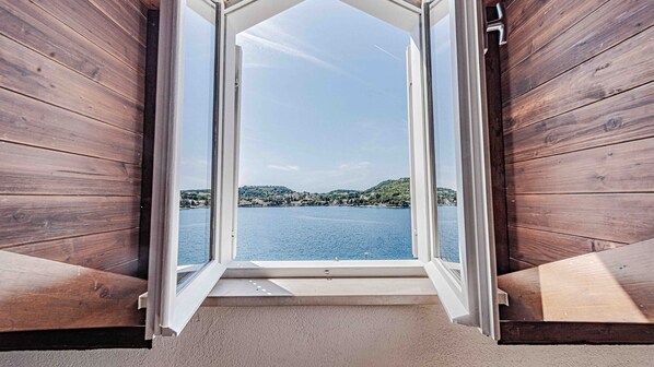 Une porte ouverte donne sur un paysage où l’on aperçoit un lac et des bâtiments situés sur la rive opposée.