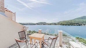Un balcon avec une table et des chaises donnant sur un lac.