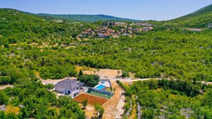 An aerial view of a residential area with houses, a swimming pool, and surrounding greenery.