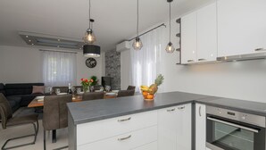 A modern kitchen with a central island, built-in oven, and pendant lighting.