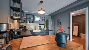 Une cuisine moderne avec un plan de travail en bois, une machine à café et un luminaire suspendu.