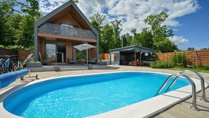 Une maison moderne à deux étages dotée d’une piscine, d’un espace salon extérieur et d’un patio couvert.