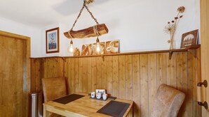 A wooden-paneled room with a wooden table, two chairs, a hanging light fixture, and wall-mounted decor. - Apartment 'Dorlar' with Private Terrace, Garden, and Wi-Fi (Schmallenberg)