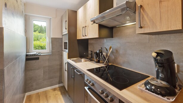 A modern kitchen with a built-in stove, oven, and coffee maker. - Apartment 'Dorlar' with Private Terrace, Garden, and Wi-Fi (Schmallenberg)