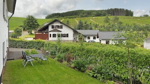 A house with a garden, a dining area with chairs and a table, and a view of a vineyard. - Apartment 'Dorlar' with Private Terrace, Garden, and Wi-Fi (Schmallenberg)