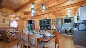 Interno di una baita in legno con zona pranzo, cucina e soggiorno.