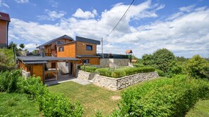A two-story house with a stone retaining wall, a wooden deck, and a stone staircase leading to the upper level. - Villa Luna - Ludbreg by Villas Guide (Ludbreg)