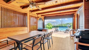An outdoor patio with a wooden table and chairs, a barbecue grill, and a view of a swimming pool. - Villa Luna - Ludbreg by Villas Guide (Ludbreg)