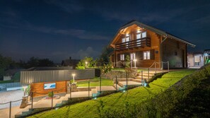 A wooden cabin with a balcony, surrounded by a well-maintained lawn and a stone wall. - Villa Luna - Ludbreg by Villas Guide (Ludbreg)