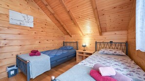 Um quarto de cabana acolhedor, com duas camas, uma mesa pequena e um quadro pendurado na parede.