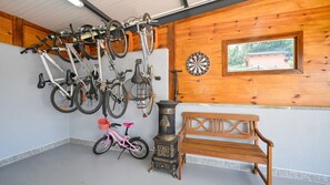 Quarto com parede de madeira, um alvo de dardos, um banco e bicicletas.