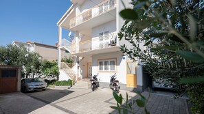 A two-story building with a balcony, a car parked in front, and a motorcycle parked in the driveway. - Apartman Fortuna pool-Makarska by Villas Guide (Makarska)