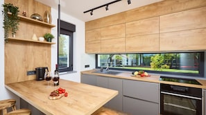A modern kitchen with wooden cabinetry, a large window, and a built-in oven.