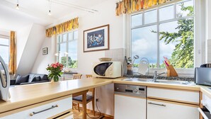 A kitchen with a dining table, a microwave, a sink, and a dishwasher. - Apartment '22' with Balcony and Wi-Fi (Sellin)