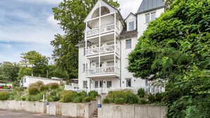 A multi-story building with a balcony, a staircase, and a white fence. - Apartment '22' with Balcony and Wi-Fi (Sellin)