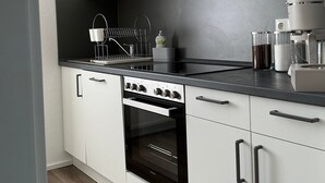 Une cuisine moderne avec des meubles blancs, un four en acier inoxydable et une hotte noire.
